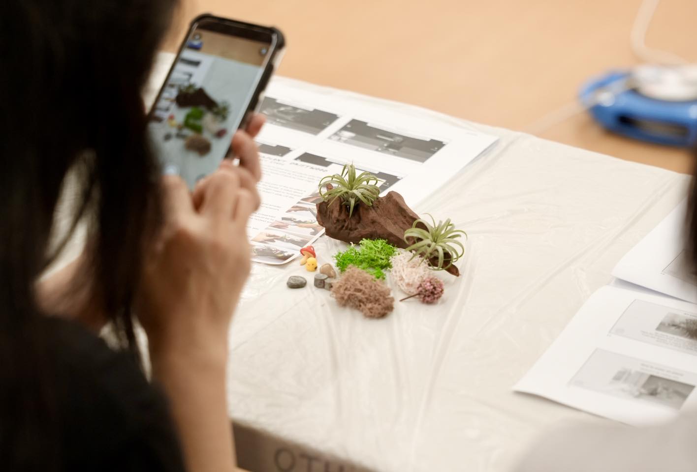 A workshop participant meticulously placing an airplant on wood