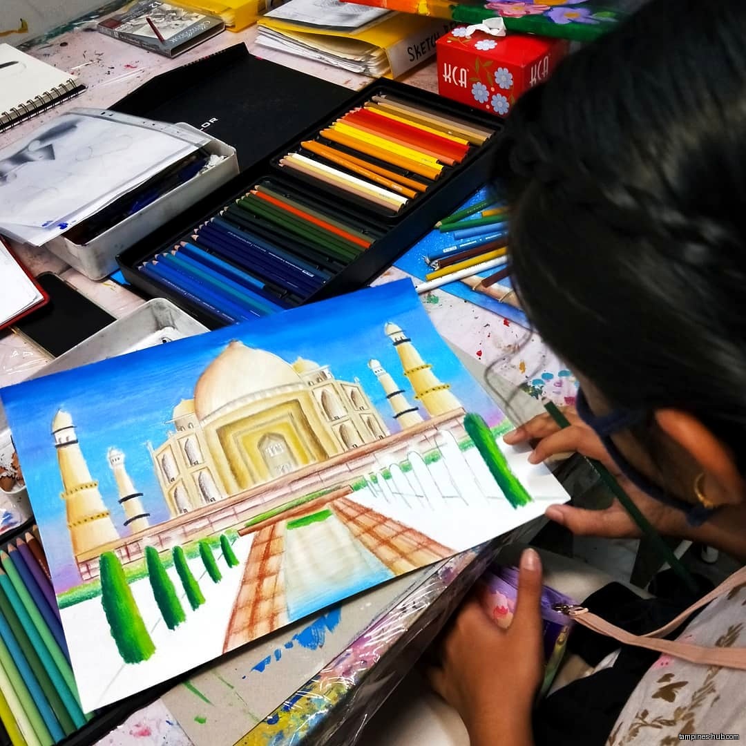 A person is drawing the Taj Mahal with colored pencils.