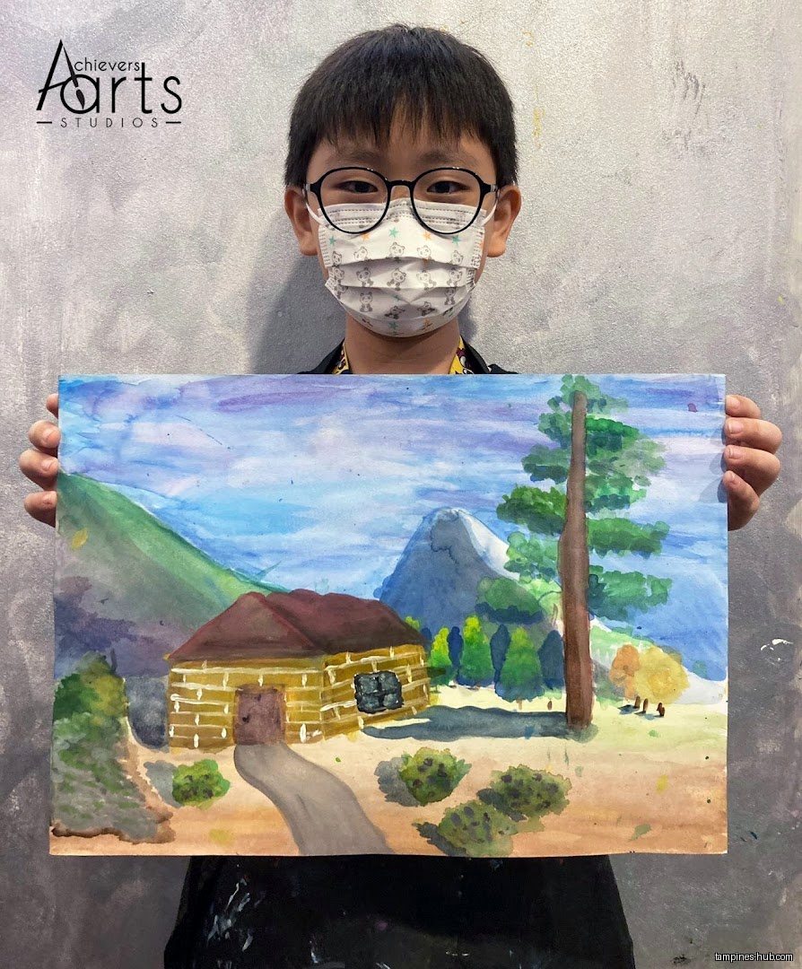 A child holds up a landscape painting in front of a gray wall.