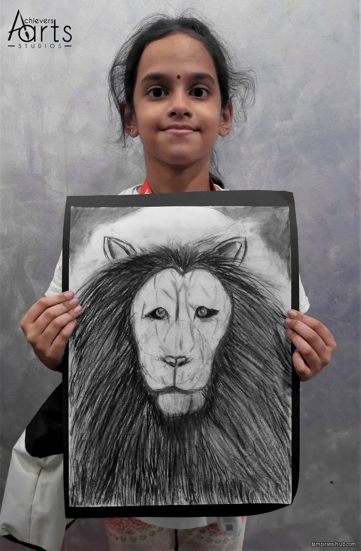 A young girl holds up a drawing of a lion's face.