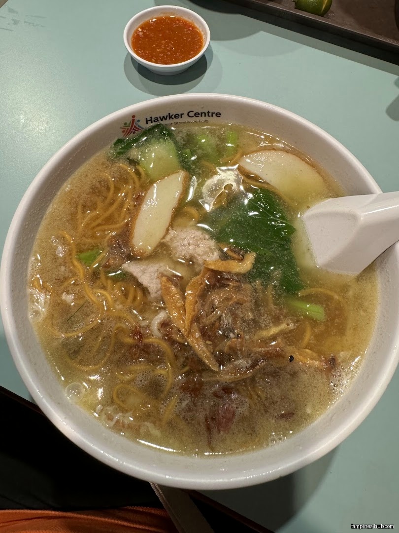 A bowl of Ban Mian soup with vegetables, fish cake, and fried anchovies.
