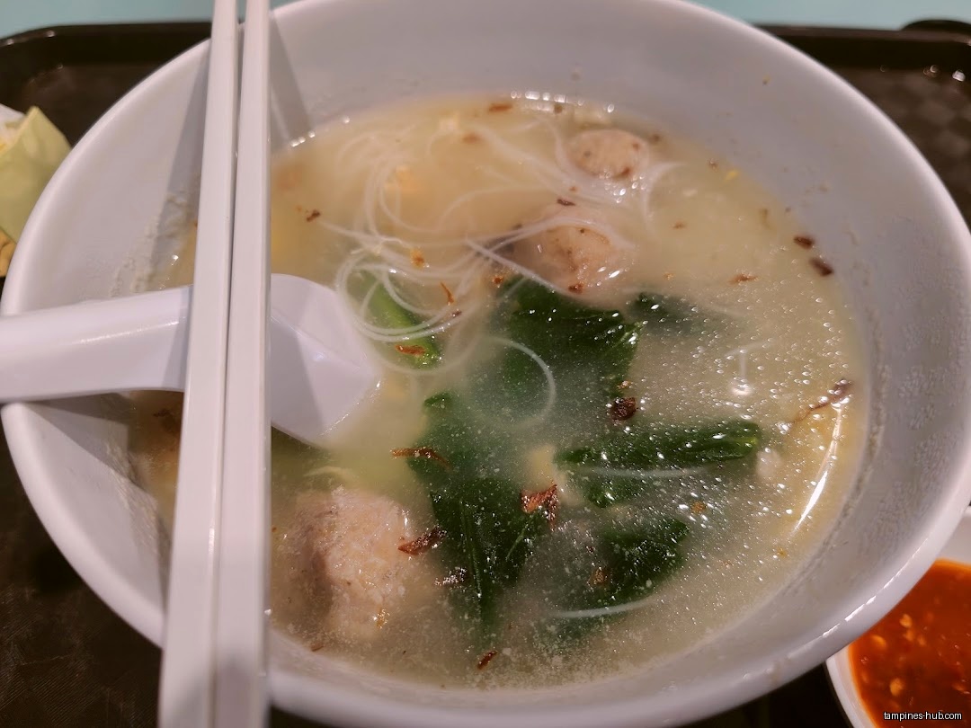 A bowl of Ban Mian soup with noodles, vegetables, and meatballs.