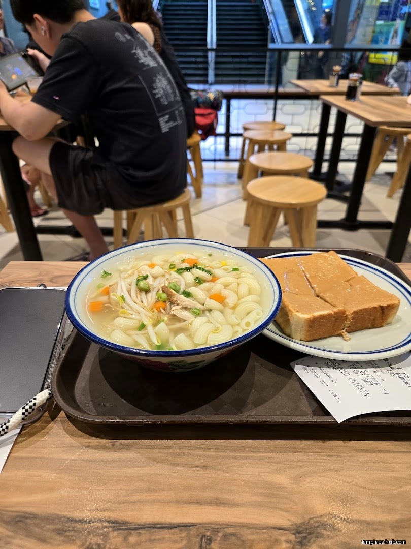 A bowl of macaroni soup and peanut butter toast on a tray.