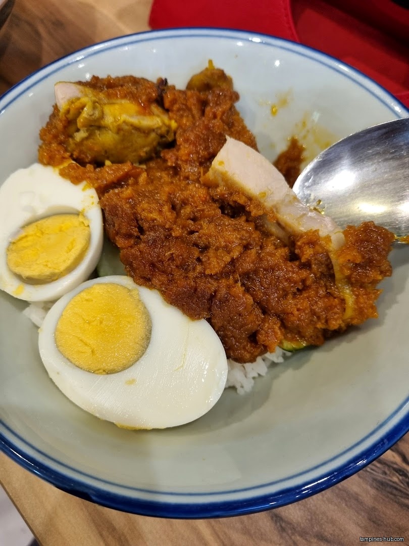 A bowl of rice with chicken curry and two halved boiled eggs.
