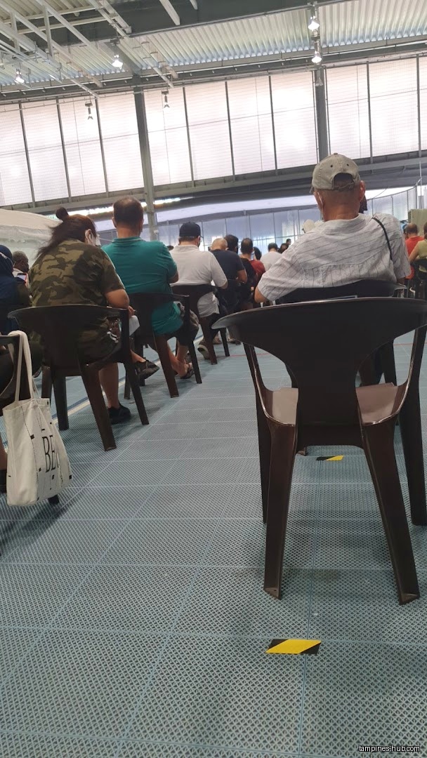 A row of people sitting in chairs in a large indoor space.