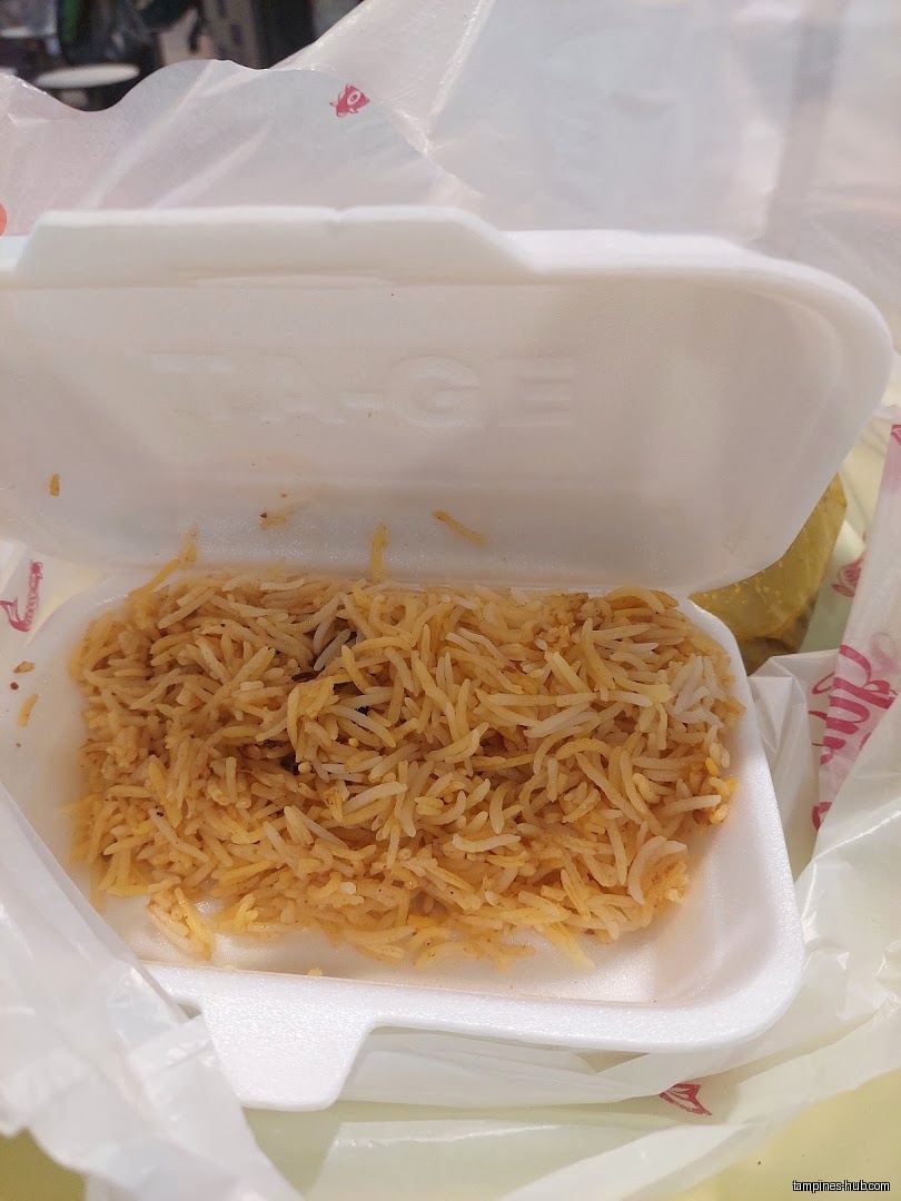 A styrofoam container holds a portion of biryani rice, partially opened.