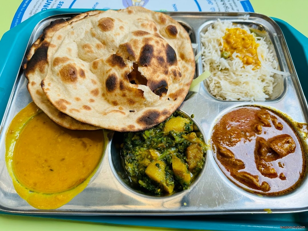 A metal tray holds Indian food including roti, rice, and curries.