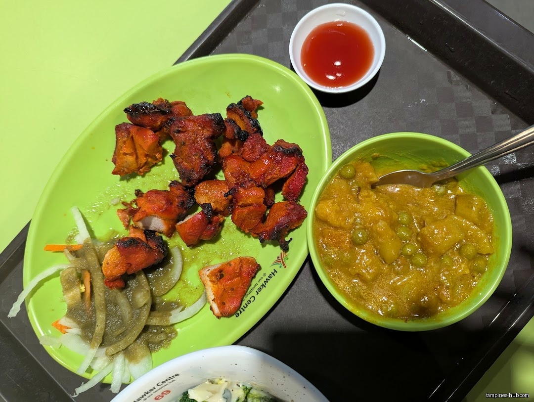 A plate of tandoori chicken, curry, and a small bowl of sauce.