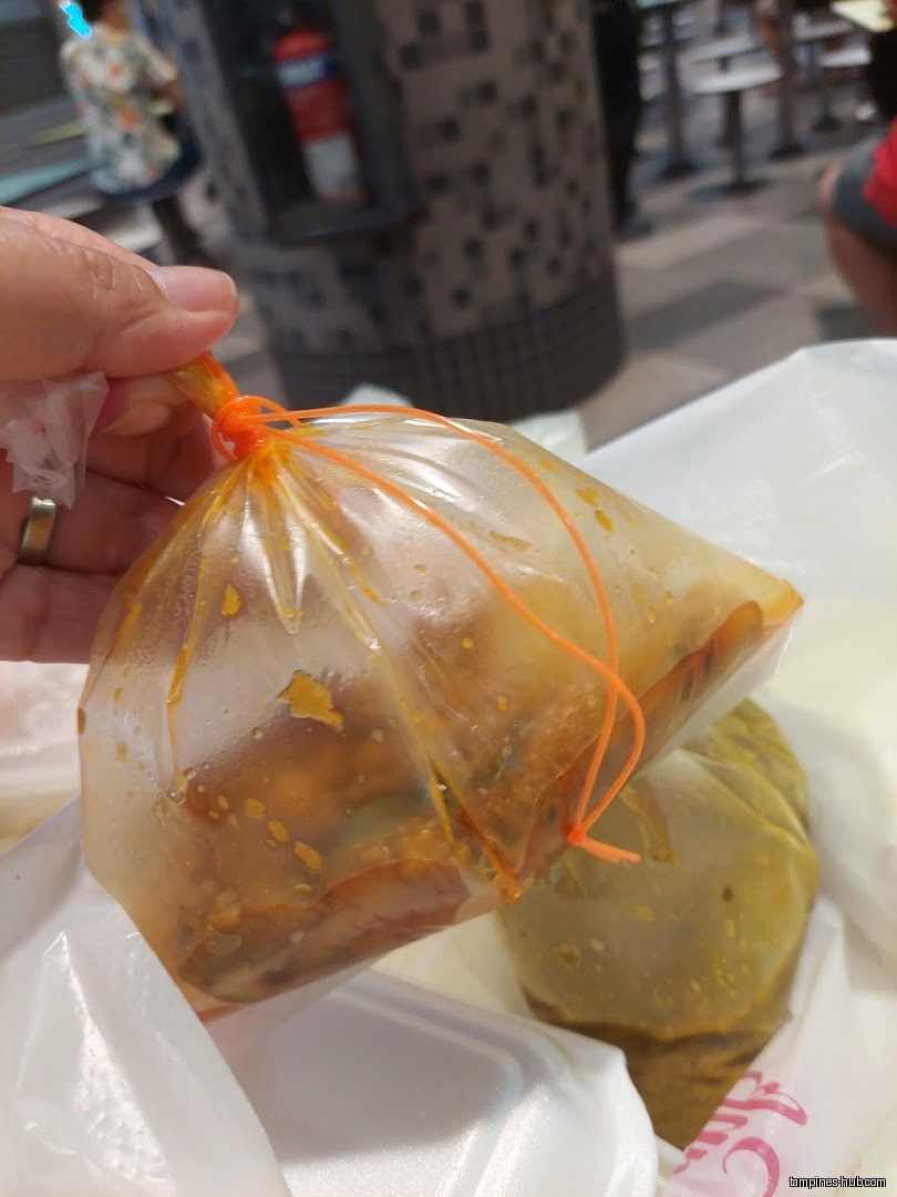 A hand holds plastic bags of food from Best Zaika.