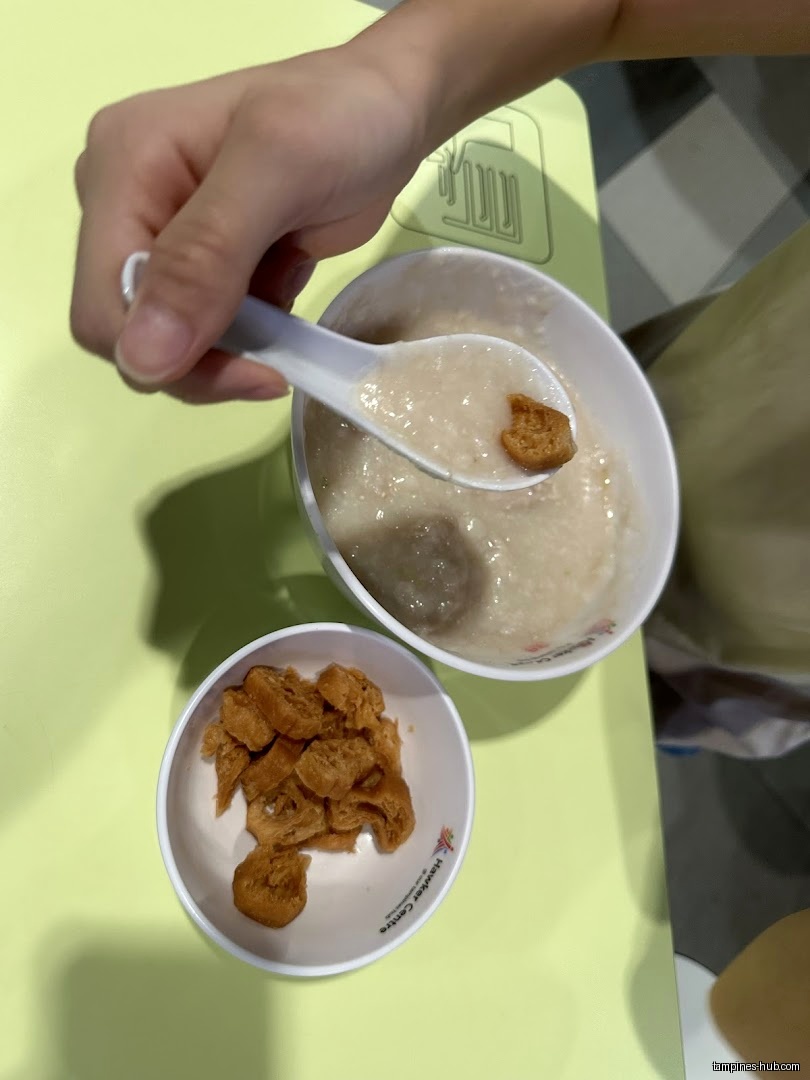 A bowl of porridge with fried dough sticks on a table.