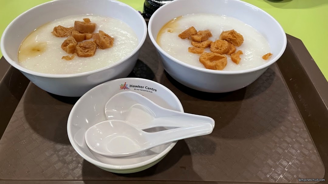 Two bowls of porridge with fried dough and spoons on a tray.