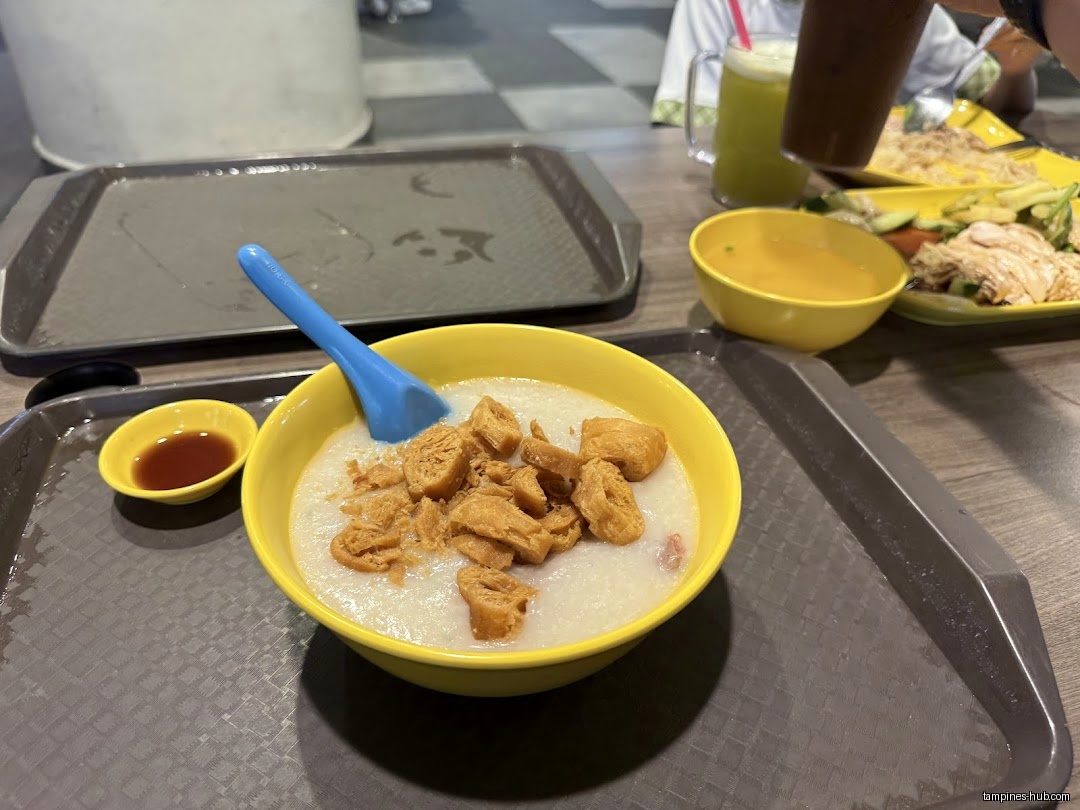 A bowl of porridge with fried dough sticks and other dishes on a table.