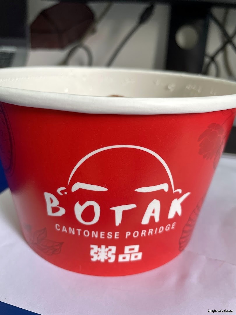 A red paper cup with the logo of Botak Cantonese Porridge.