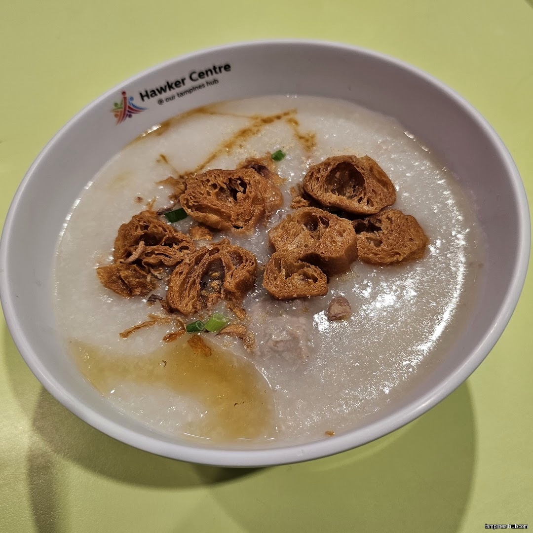 A bowl of Cantonese porridge topped with fried dough and green onions.