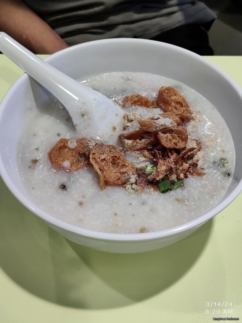 A bowl of Cantonese porridge with fried dough and other toppings.