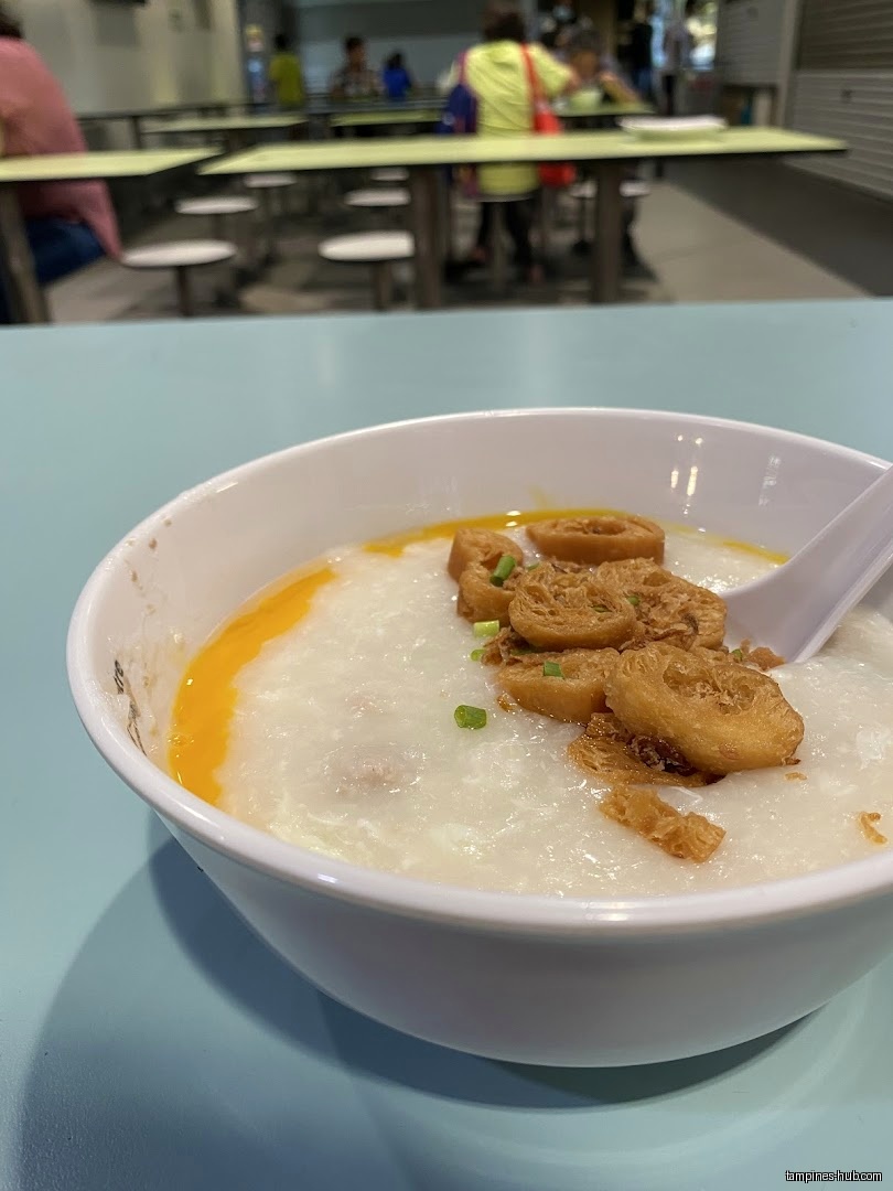 A bowl of Cantonese porridge with fried dough sticks and egg yolk.