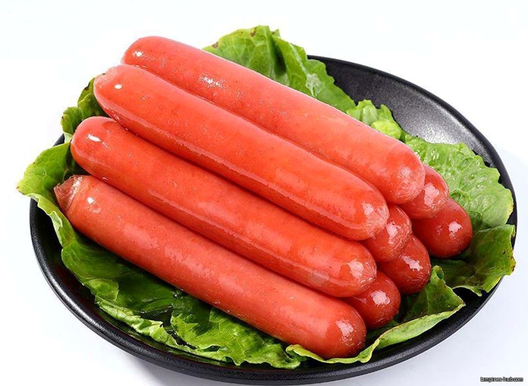 A plate of red sausages is arranged on green lettuce leaves.