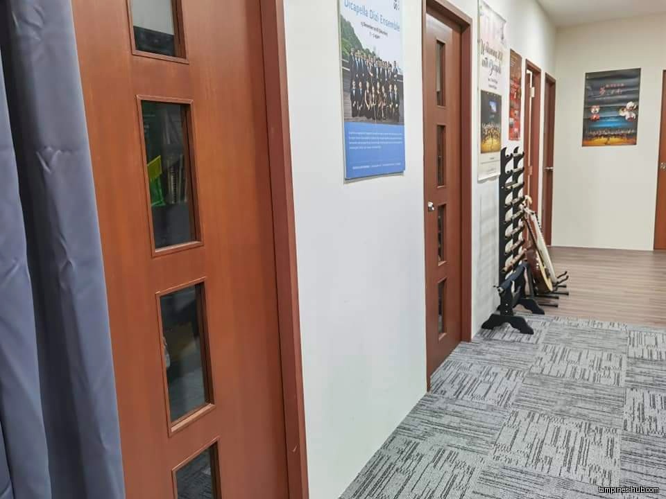 A hallway with doors, posters, and musical instruments in a rack.