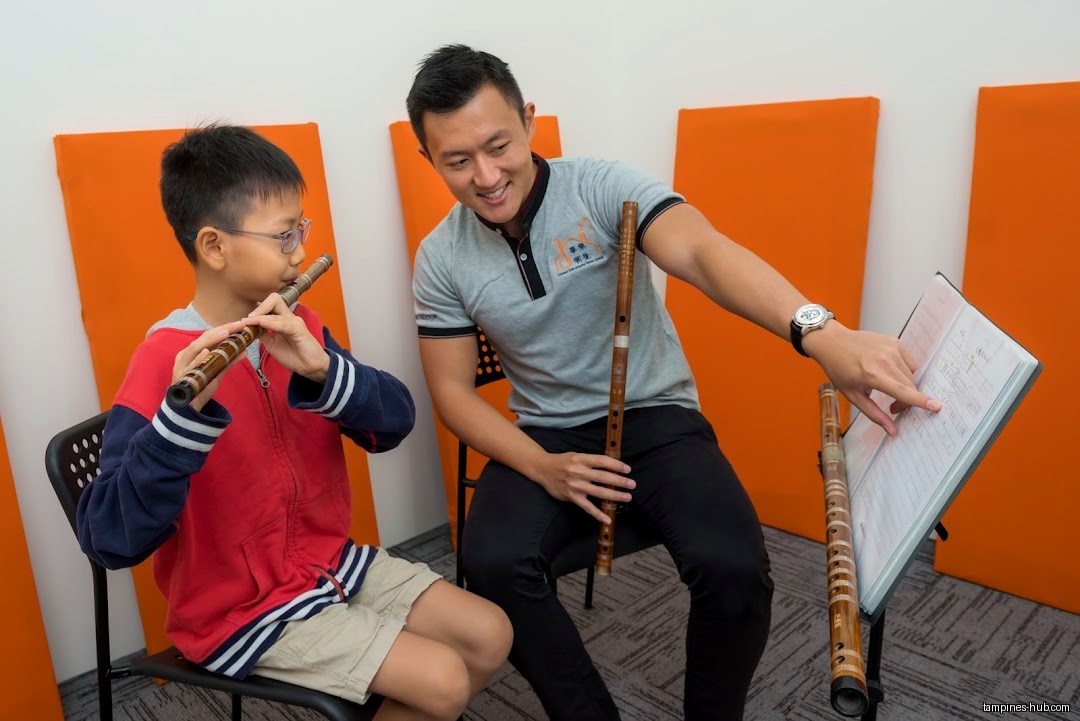 A student learns to play the flute with an instructor.