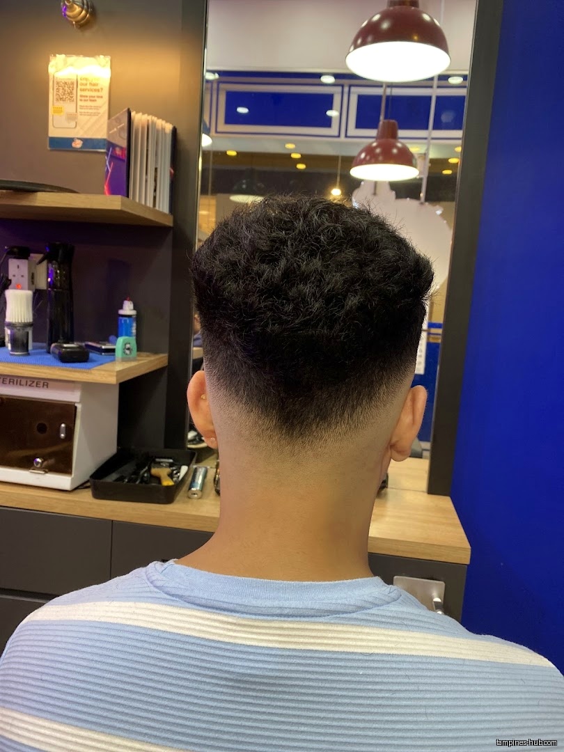 A man's head with a fresh fade haircut in a barber shop.