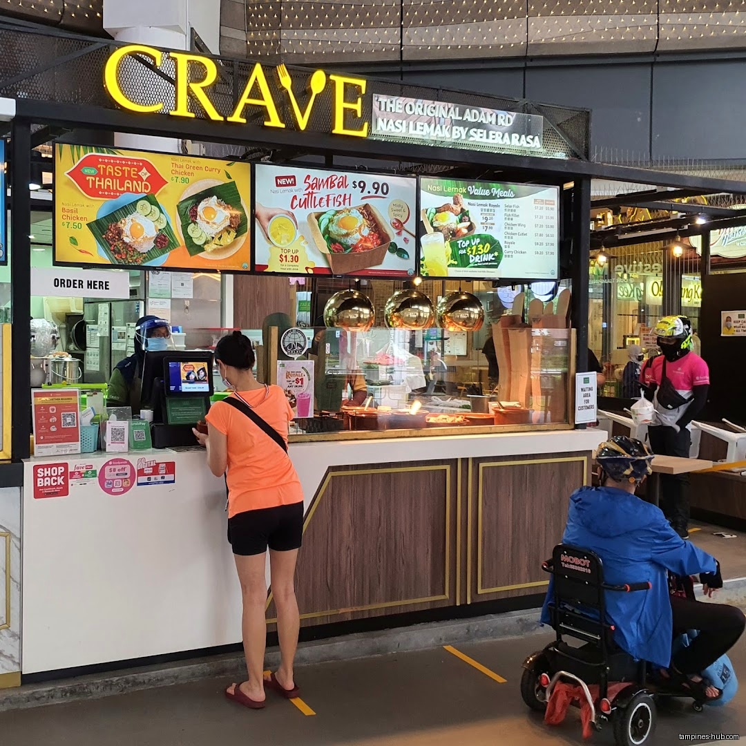 Crave Nasi Lemak shop front with customers and menu boards.