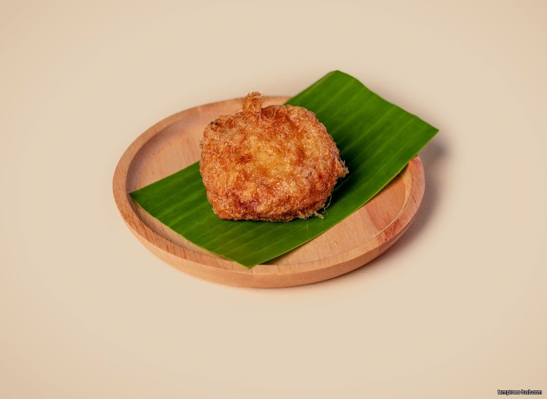 A fried food item on a banana leaf, placed on a wooden plate.