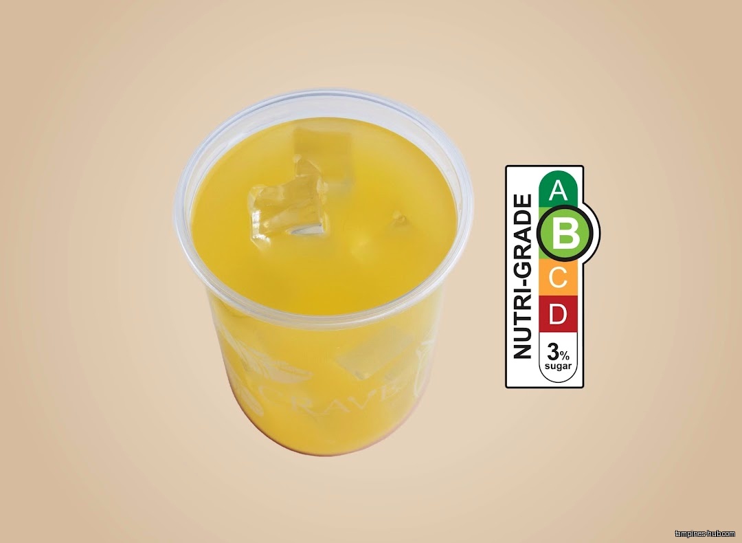 A cup of yellow drink with ice and a Nutri-Grade B label.