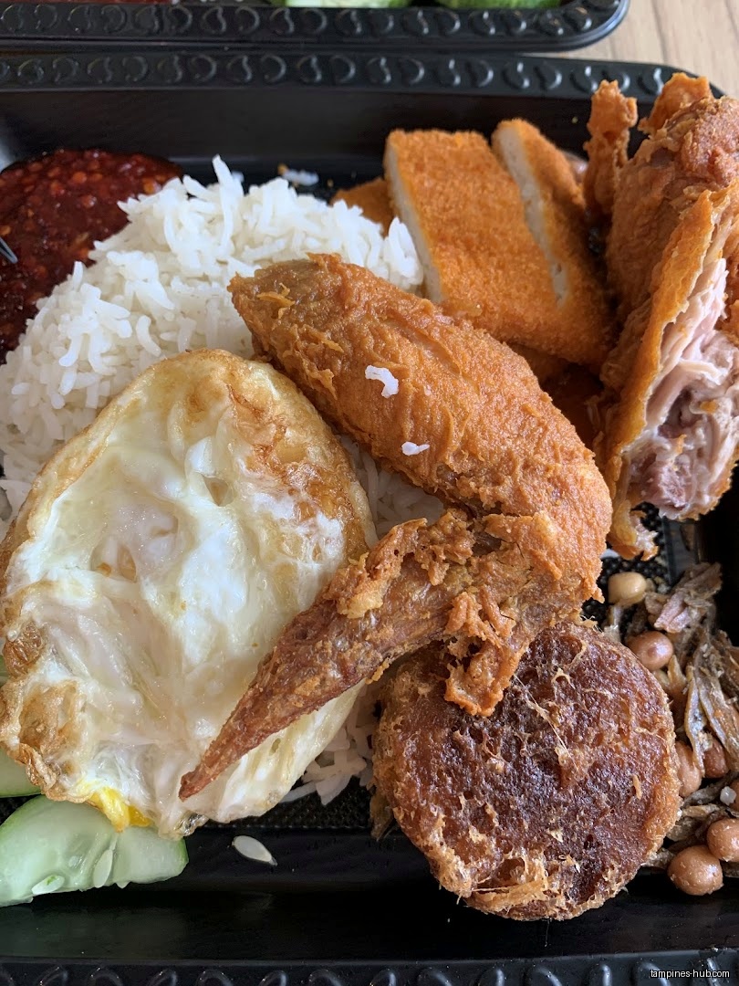 Close-up of a Nasi Lemak dish with rice, egg, and fried chicken.