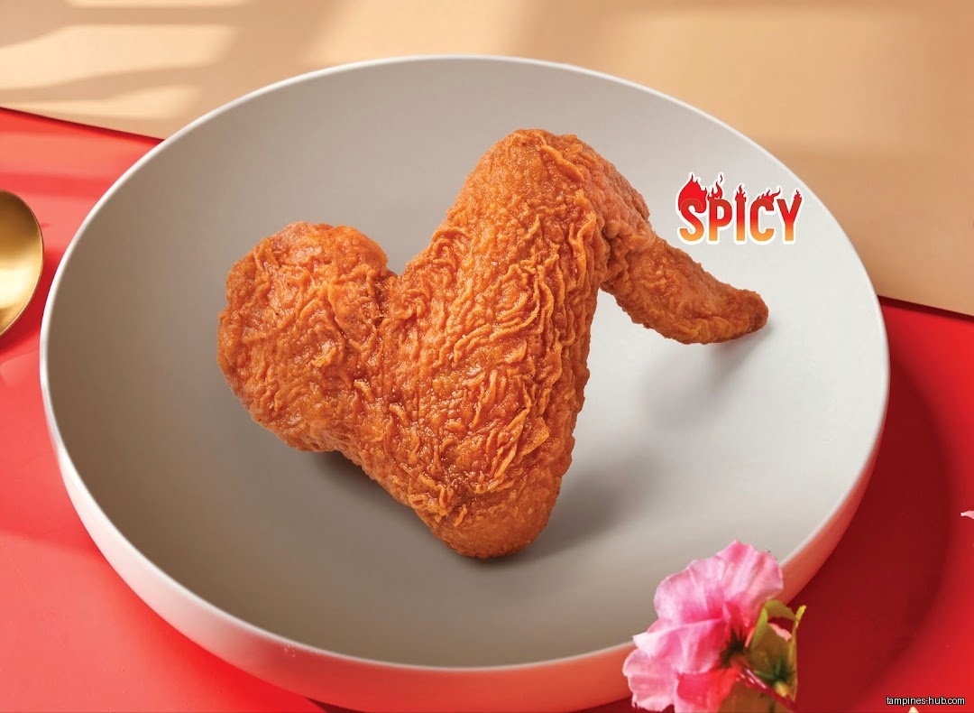 A spicy fried chicken wing is displayed on a plate with a flower.