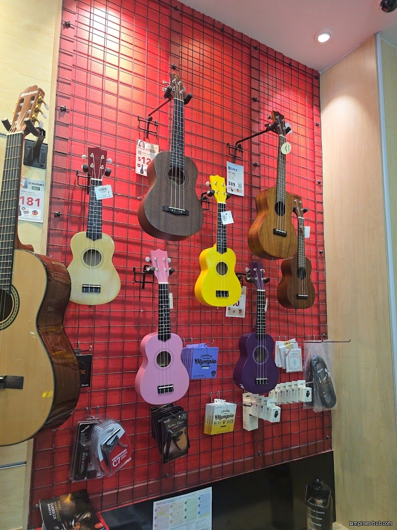 A display of ukuleles and a guitar hang on a red grid wall.