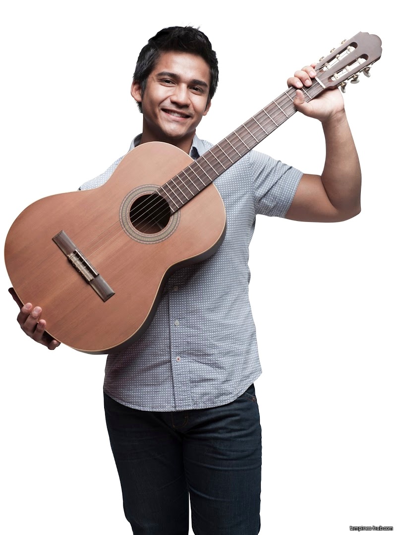 Smiling man holding a classical guitar, likely for Cristofori Music School.