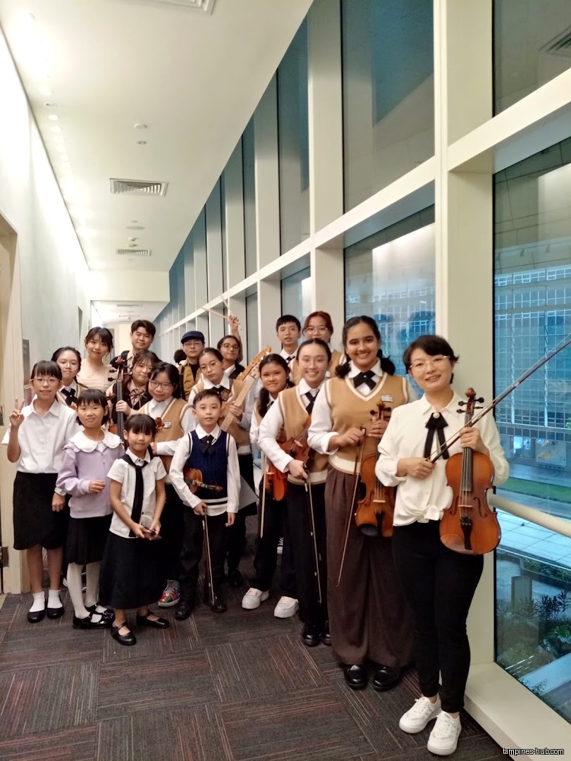 A group of students and teachers pose with violins at Cristofori Music School.