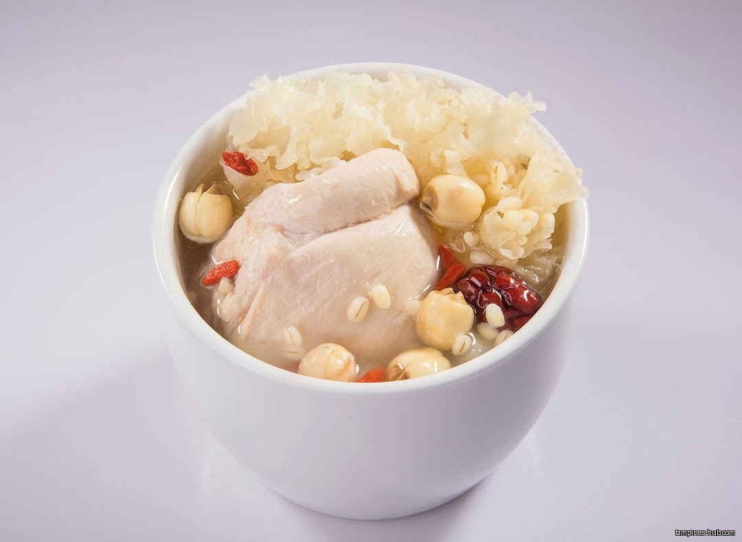 A bowl of herbal soup with chicken, lotus seeds, and white fungus.