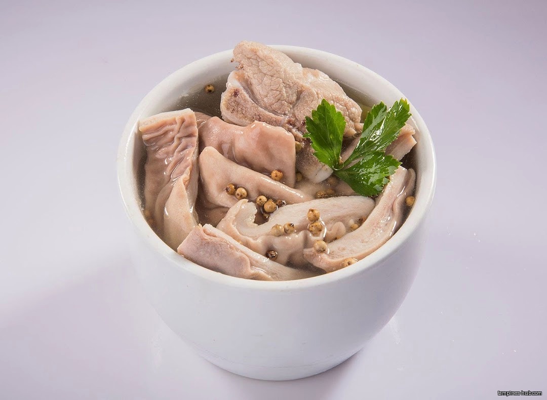 A bowl of herbal soup with meat and intestines, garnished with parsley.