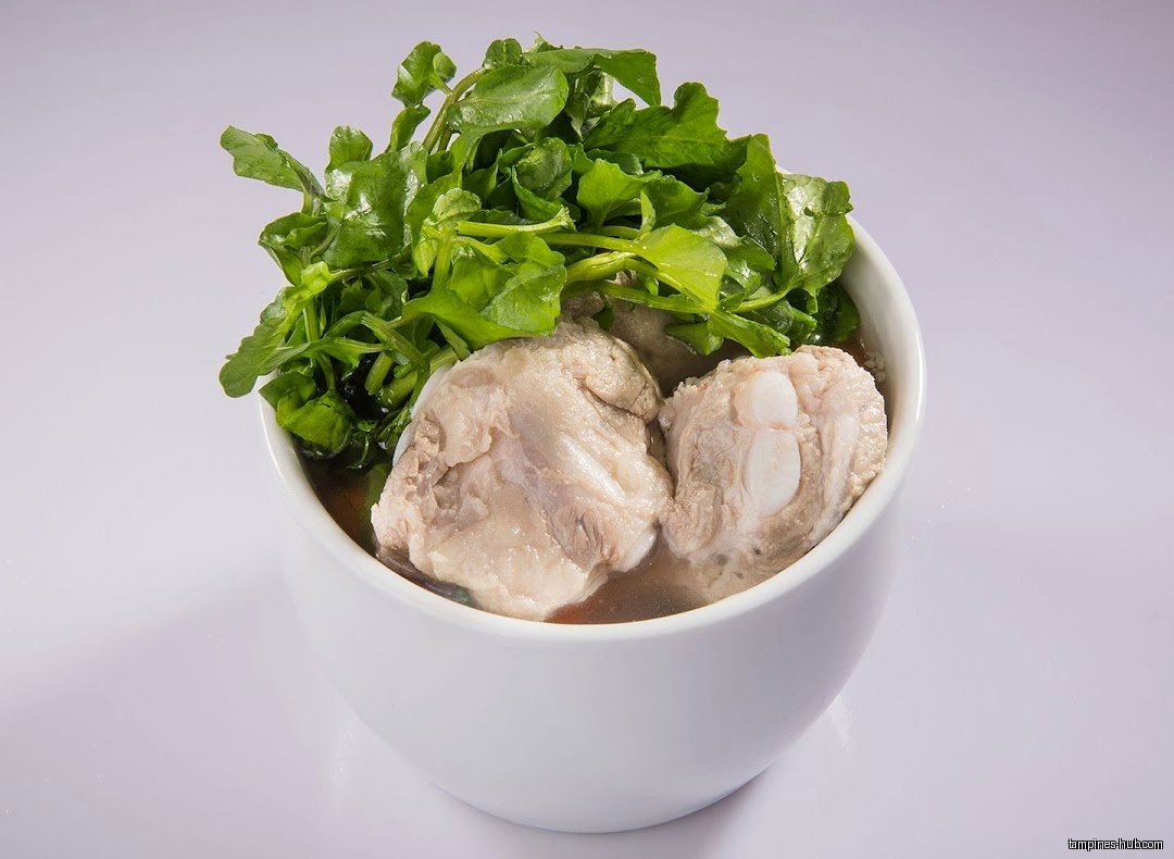 A bowl of herbal soup with meat and green vegetables.