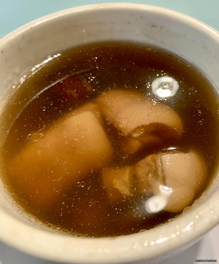 A close-up shot of herbal soup with meat in a bowl.