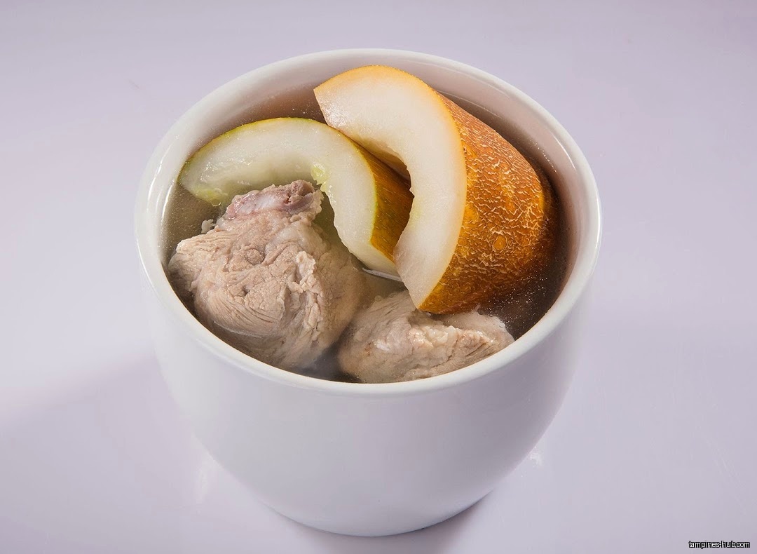 A bowl of herbal soup with meat and melon slices.