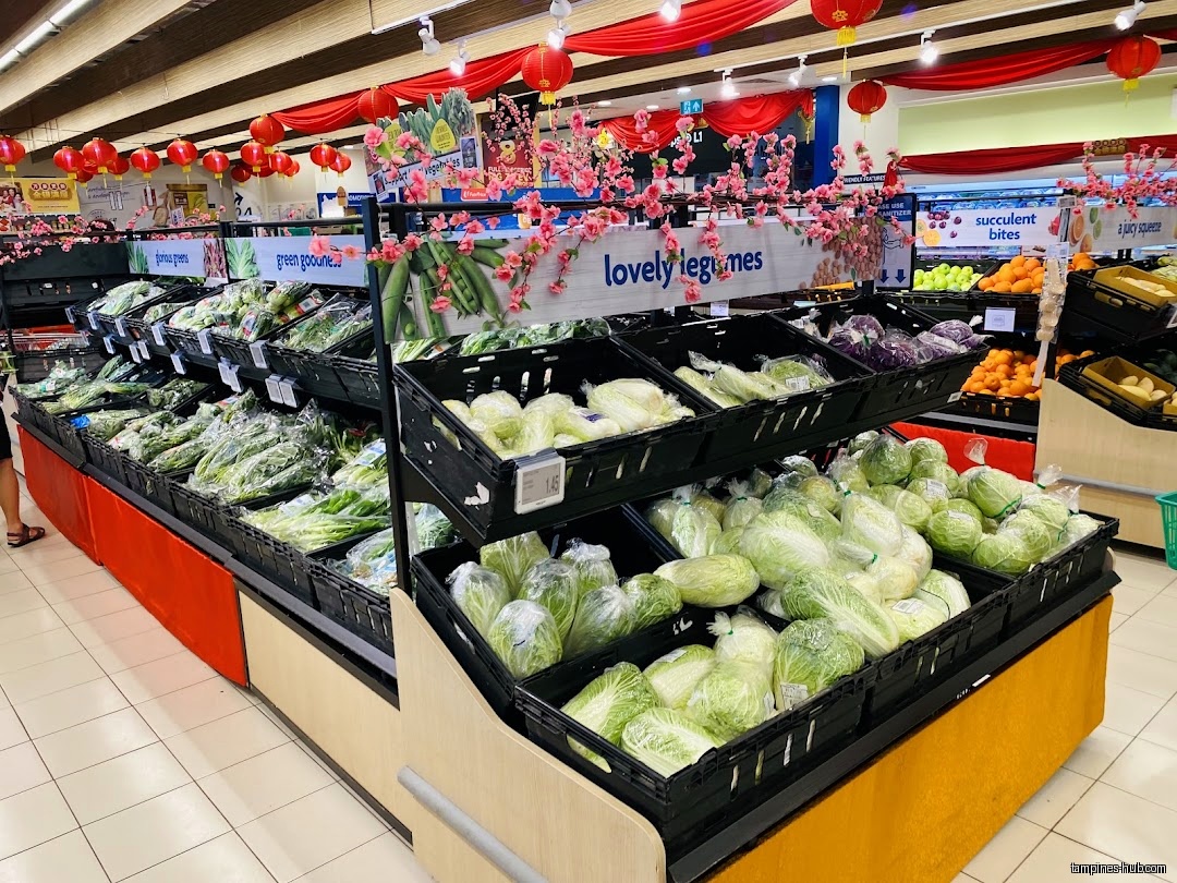 FairPrice Our Tampines Hub displays fresh vegetables in black crates under red lanterns.