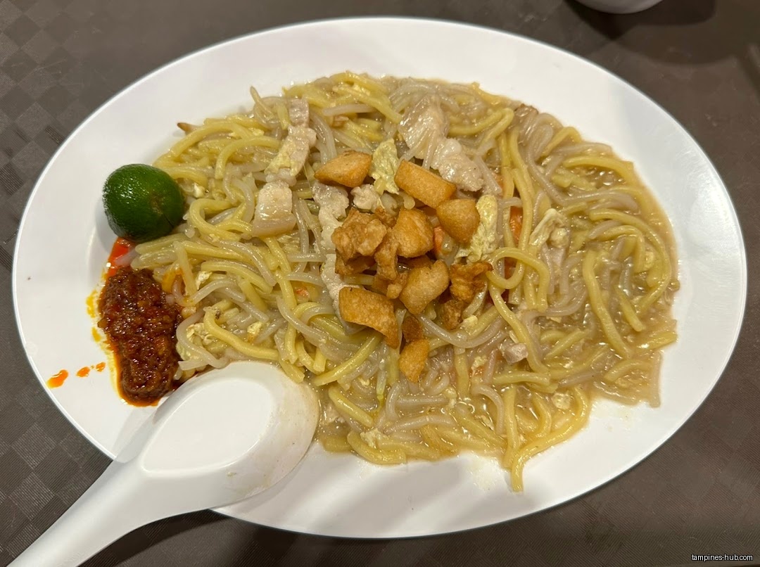 A plate of Hokkien mee with lime, chili, and pork lard.