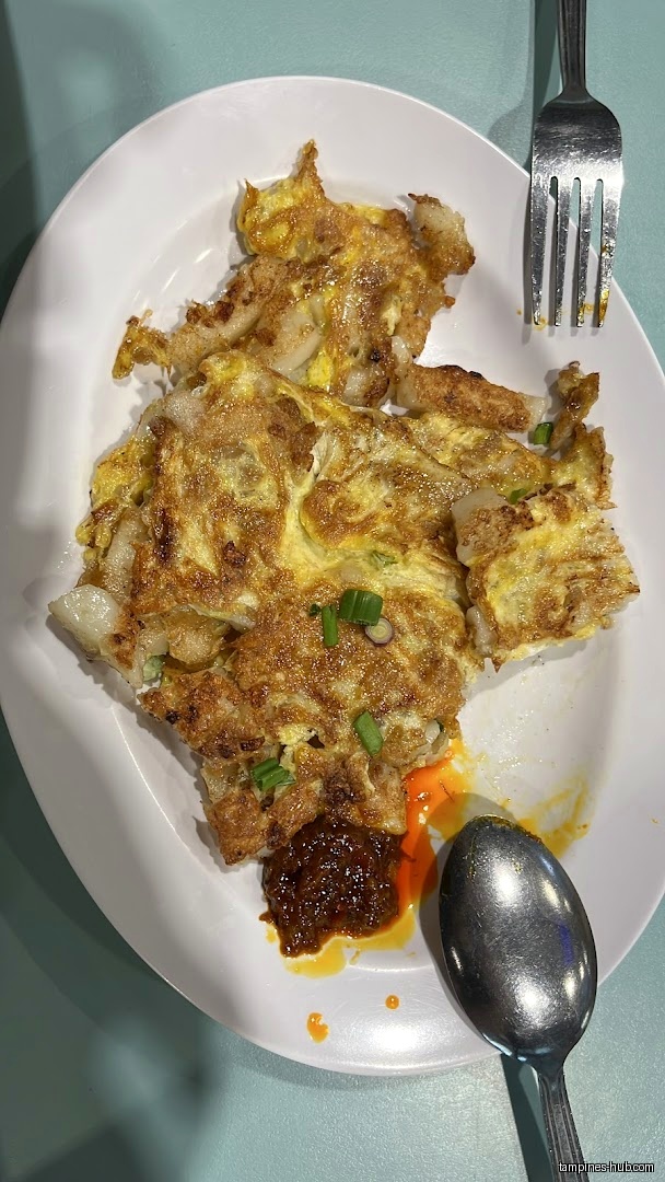 Overhead shot of a plate of fried carrot cake with chili sauce.