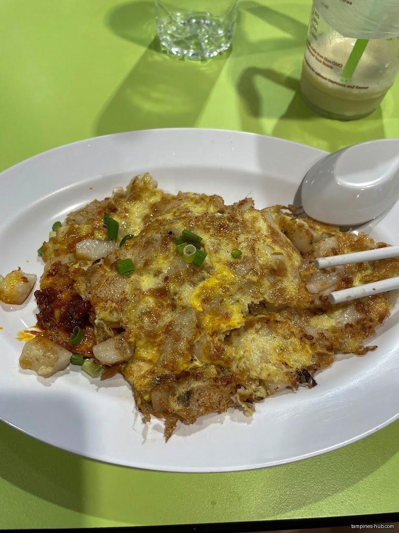 A plate of fried carrot cake with chopsticks and a spoon.