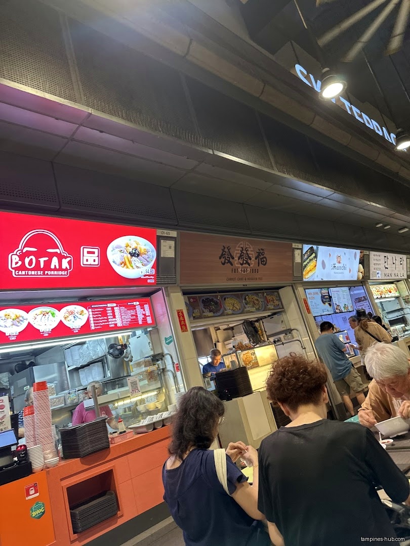 Customers line up at a food stall with menus and food displays.