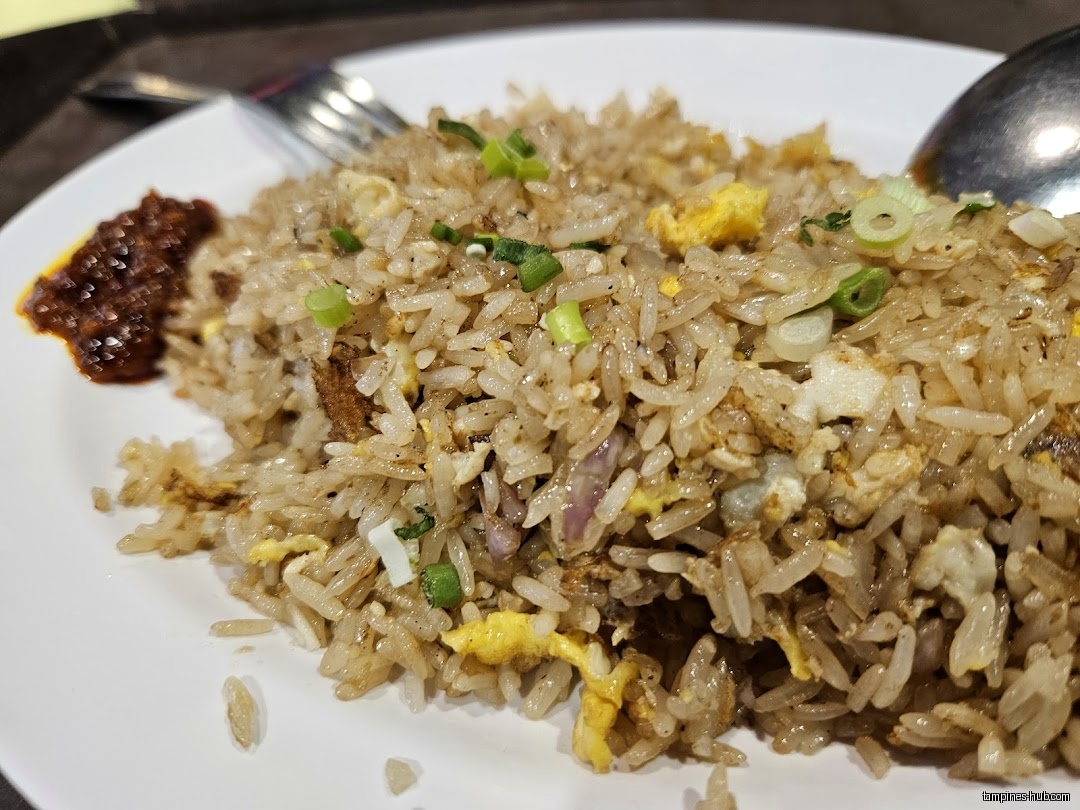A plate of fried rice with a side of chili sauce.