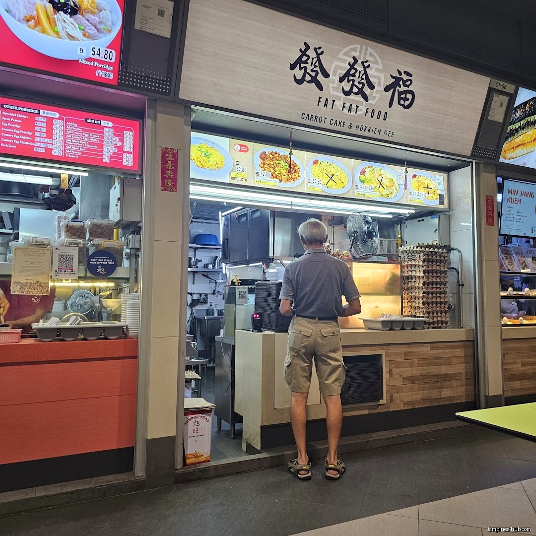 A man stands at the counter of Fat Fat Food, a food stall.