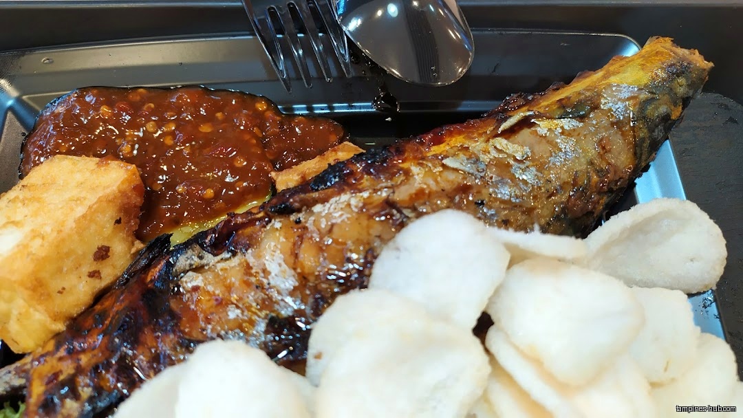A plate of grilled fish with tofu, chili sauce, and crackers.