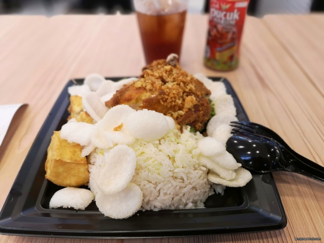 A plate of rice, fried chicken, tofu, and crackers is on a table.