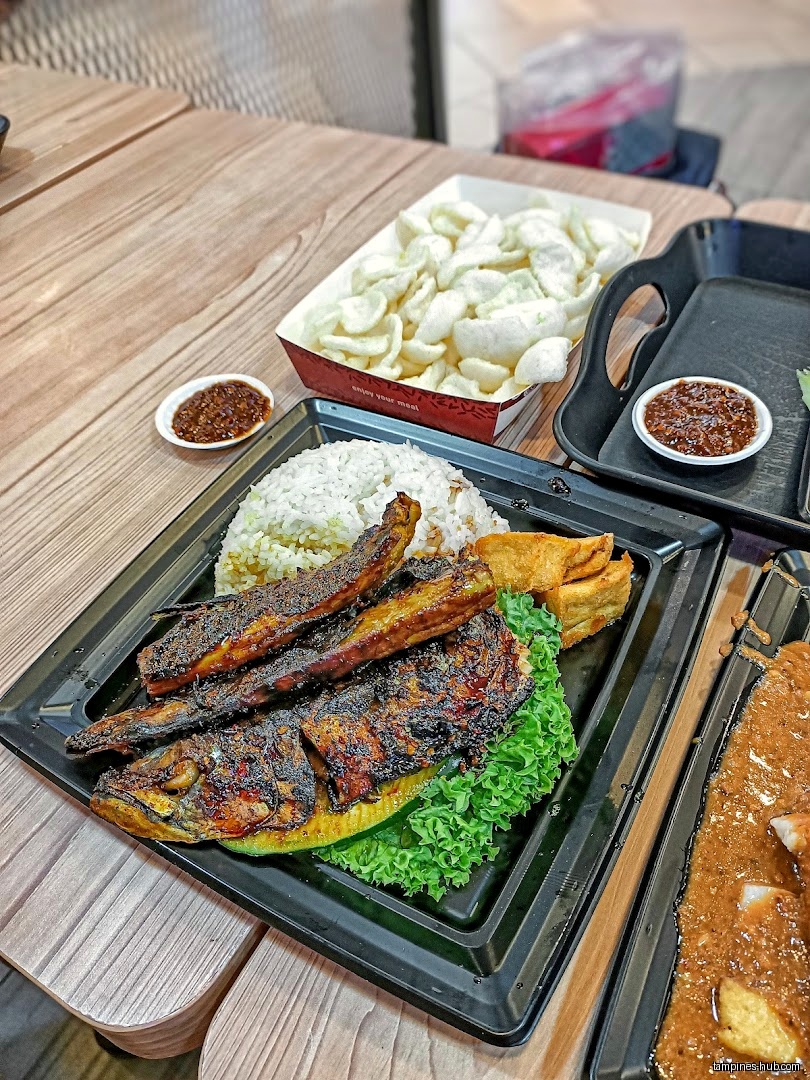 Grilled fish with rice, tofu, crackers, and chili sauce on a tray.