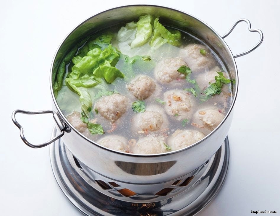 A pot of soup with meatballs and lettuce is shown.