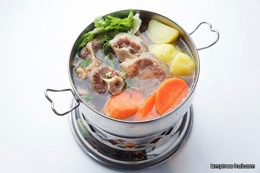 A pot of oxtail soup with vegetables, carrots, and potatoes.