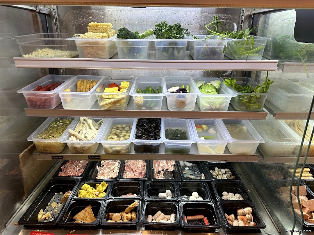 A refrigerated display case shows various food ingredients in clear and black containers.